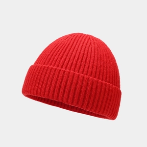 Close-up of high-quality red ribbed knit texture on a minimalist retro beanie hat