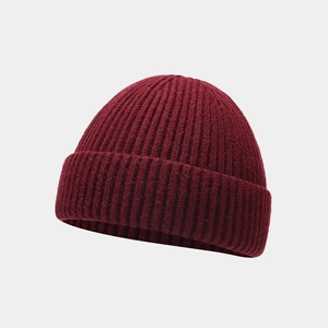 Macro detail of the wine red knitted beanie showing soft ribbed texture and folded cuff