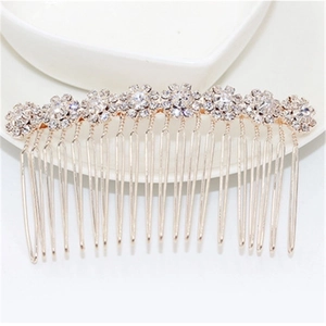 Detail of a golden metal hair comb with sparkling rhinestones on a white ceramic dish