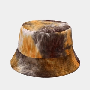 Macro detail of tie-dye corduroy fabric texture on a bucket hat with yellow and brown tones