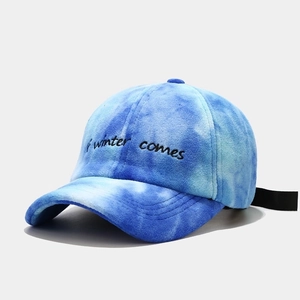 Detail of blue tie-dye plush baseball cap featuring black 'if winter comes' embroidery