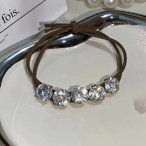 Close-up of brown elastic hair tie featuring five sparkling round rhinestones on a tray