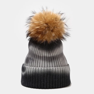 Close-up of tie-dye knit beanie with fluffy raccoon fur pom-pom and gradient texture