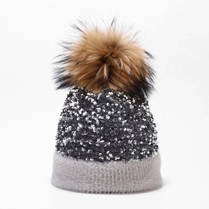 Macro view of sparkly silver sequins on winter knitted hat with a large faux fur pompom