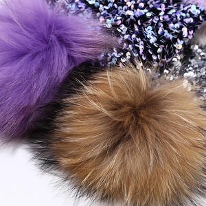 Women's winter knit hat with colorful sequin fabric and large raccoon fur pom pom