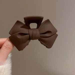 Macro detail of the matte brown bow hair claw clip showing its smooth frosted texture