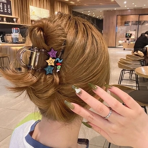 Star-patterned brown hair claw clip shown in a stylish updo on a model in a cafe setting