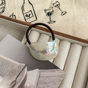 Close-up of semi-circle hair tie with iridescent pearlescent finish on a wooden tray