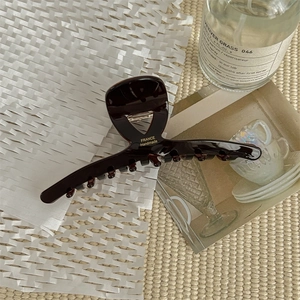 Detail of dark brown acetate hair claw clip with golden France Handmade lettering text