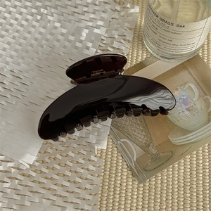 Close-up of dark brown tortoiseshell acetate hair claw with golden Bométte engraving