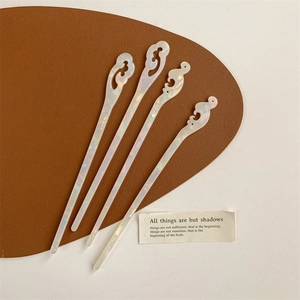 Set of 4 pearlescent white hair sticks with cloud pattern on brown leather surface