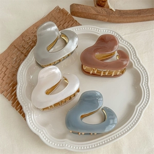 Set of four glossy acetate hair claws in gray, brown, white and blue on a vintage plate