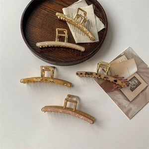 Elegant metal claw hair clips in various patterns including tortoiseshell and ivory white