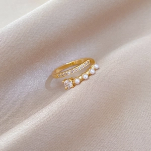 Minimalist adjustable gold ring with elegant pearls and sparkling zircon on satin background
