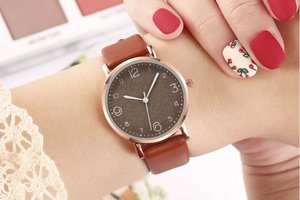 Women's quartz watch with rose gold case, brown textured dial and leather strap on wrist