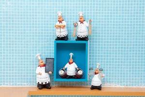 Detailed set of five vintage chef figurines holding kitchen tools on wooden table