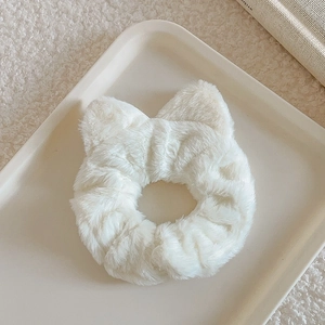 Detailed view of white faux fur scrunchie with cute cat ears on a minimal display tray
