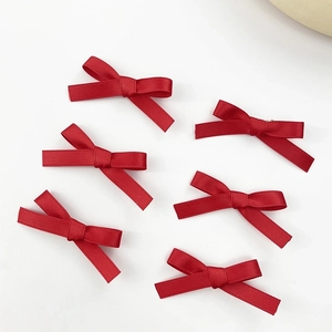 Detailed view of six red satin ribbon bows for hair accessories set on white background