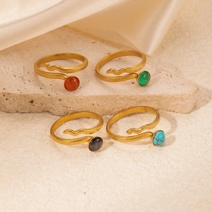 Elegant gold snake rings with colorful gemstones on a minimalist stone background