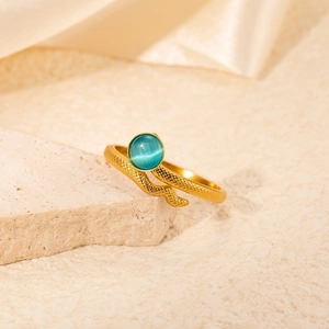 Macro shot of gold snake ring featuring a teal gemstone on a soft beige silk background