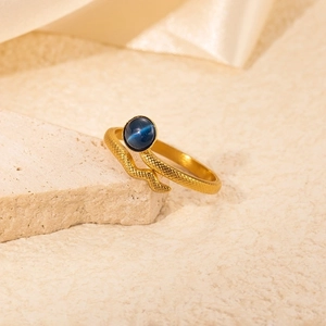 Detailed macro view of a golden snake ring featuring a blue cat-eye stone and scale texture