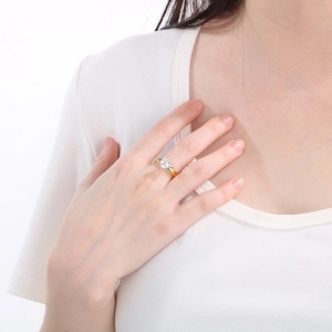 Close-up of a minimalist gold titanium steel four-prong ring with a round zircon on a finger