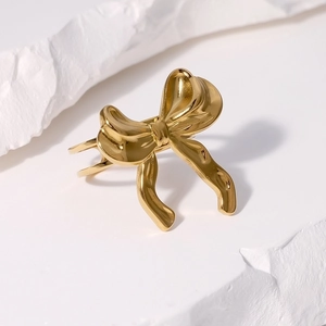 Minimalist golden bow stainless steel open ring on a textured white background