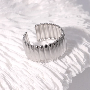 Macro detail of silver wide band ring with vertical ribbed texture on artistic white base