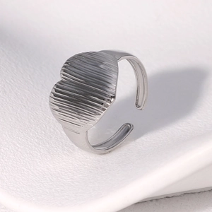 Macro view of silver heart ring featuring vertical striped texture and adjustable opening