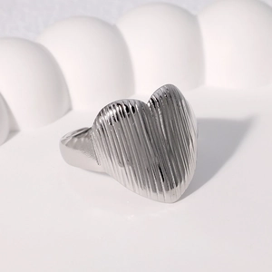Minimalist silver heart ring with vertical ribbed texture on a white wavy art background