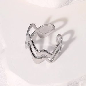 Macro shot of silver irregular wavy stainless steel ring on white textured stone background