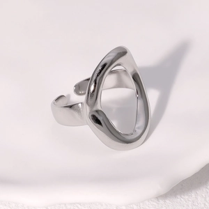 Macro view of polished silver geometric oval ring showing fluid lines on white ceramic