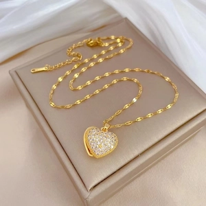 Elegant gold titanium necklace with sparkling heart pendant on a champagne jewelry box