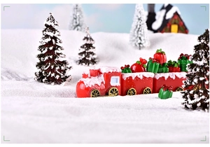 Close-up of a miniature red Christmas train with gifts on a snowy winter landscape