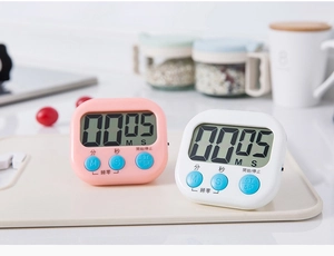 Macro detail of kitchen digital timers in pink and white with large LCD display and blue buttons
