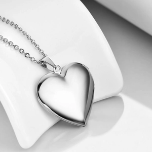 Macro shot of polished silver heart locket pendant with delicate stainless steel rolo chain