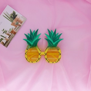 Macro view of pineapple-shaped party sunglasses with yellow frames and green leaf accents