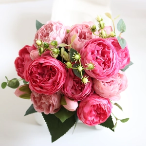 Macro detail of artificial pink peony silk bouquet with layered petals and green leaves