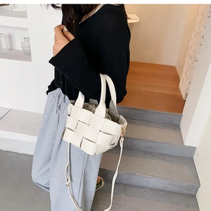Close-up of a white woven leather mini bucket bag with a stylish top handle and strap
