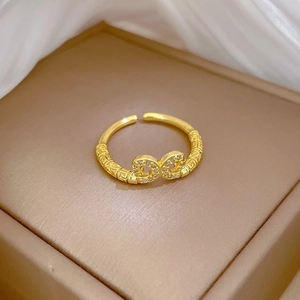 Adjustable gold plated infinity ring with white zircon and vintage pattern on silk background