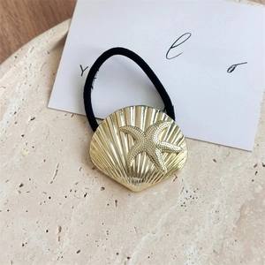 Detail of golden seashell and starfish charm on black elastic hair tie for ponytail