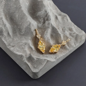 Macro shot of 18k gold plated earrings with marquise-cut yellow zircon and heart accent