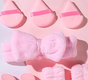 Pink flannel beauty set with bow headband, wristbands, and soft makeup sponges