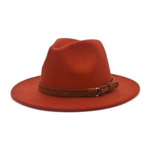 Detail of burnt orange fedora hat featuring a brown suede band with a gold buckle and tassel
