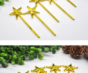 Detail of shiny gold star wand decoration with pine cones and green plants for Christmas party