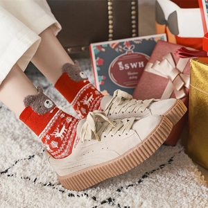 Festive red Christmas socks with beige platform suede shoes on a cozy winter carpet