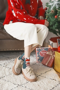 Close-up of green Christmas socks with Santa Claus pattern and beige suede platform sneakers