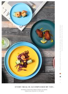 Vertical view of colorful matte ceramic plates with fresh salad, shrimp and wings on wooden table