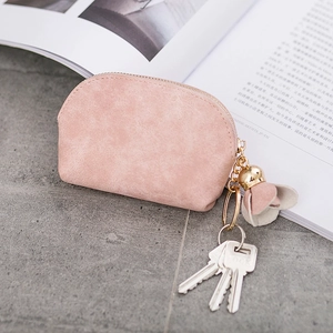 Close-up of pink suede coin purse with decorative tassel and metal keys on a book