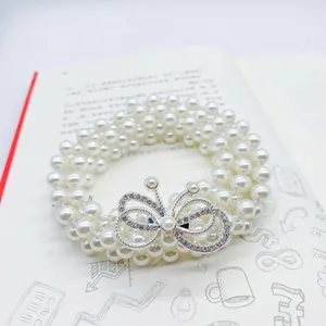 Detail of multi-layer pearl waist belt featuring a sparkling rhinestone butterfly buckle